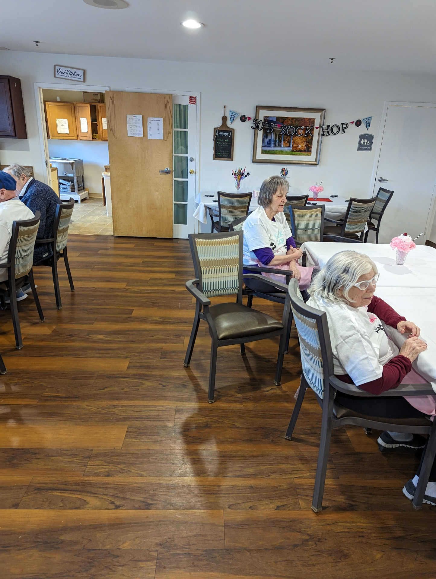 Residents seated at tables decorated for a fifties Sock Hop event.