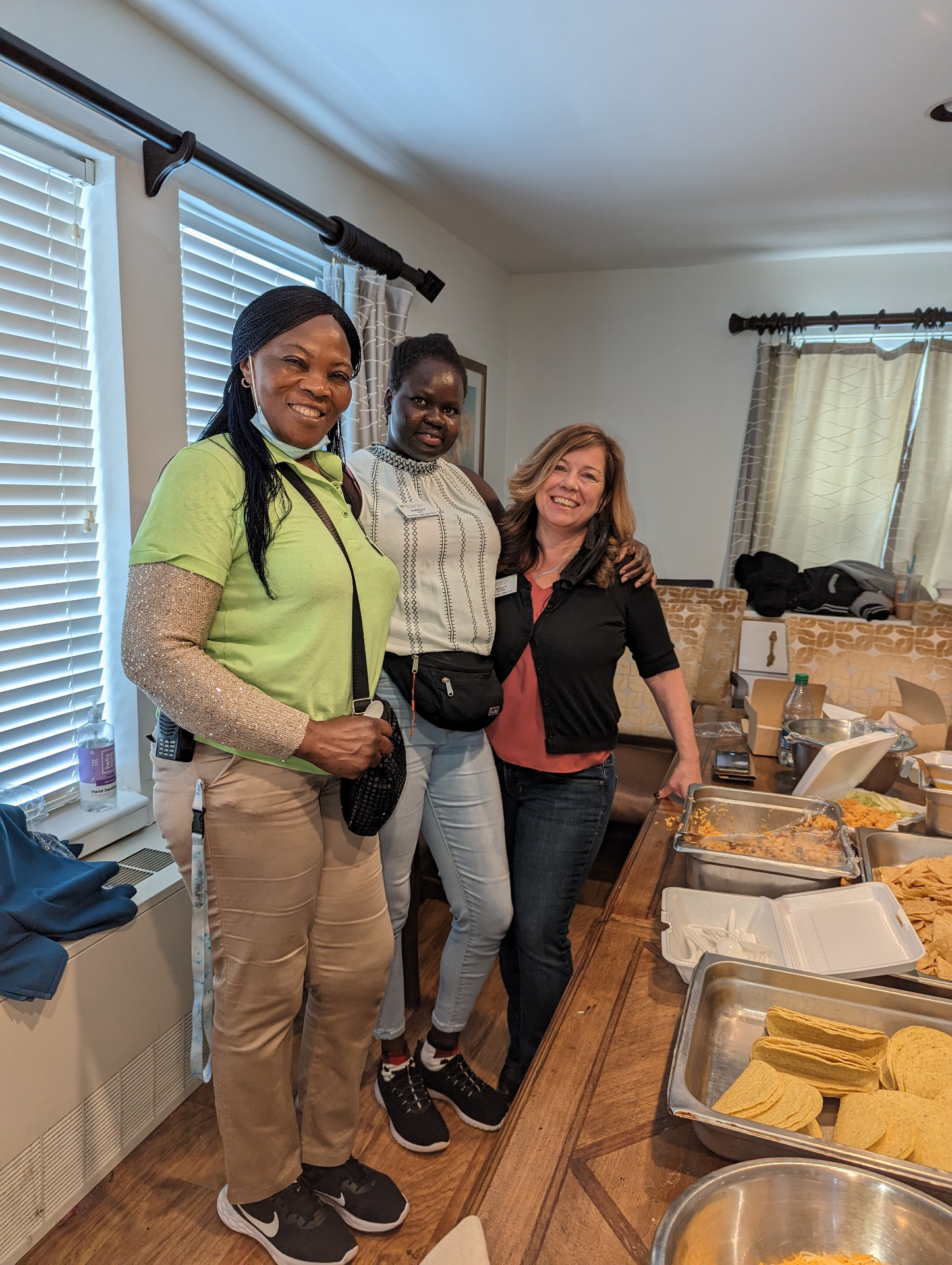 Three members of the care team smiling together next to a taco buffet at a community event.